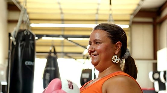 Woman in a boxing gym with pink boxing gloves